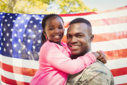 A servicemember holds a young girl.
