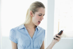 Angry businesswoman reads text on smartphone