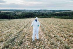 Worker in field using Roundup in Canada