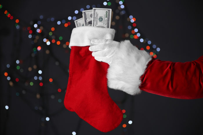 santa holding on to christmas stocking filled with settlement money