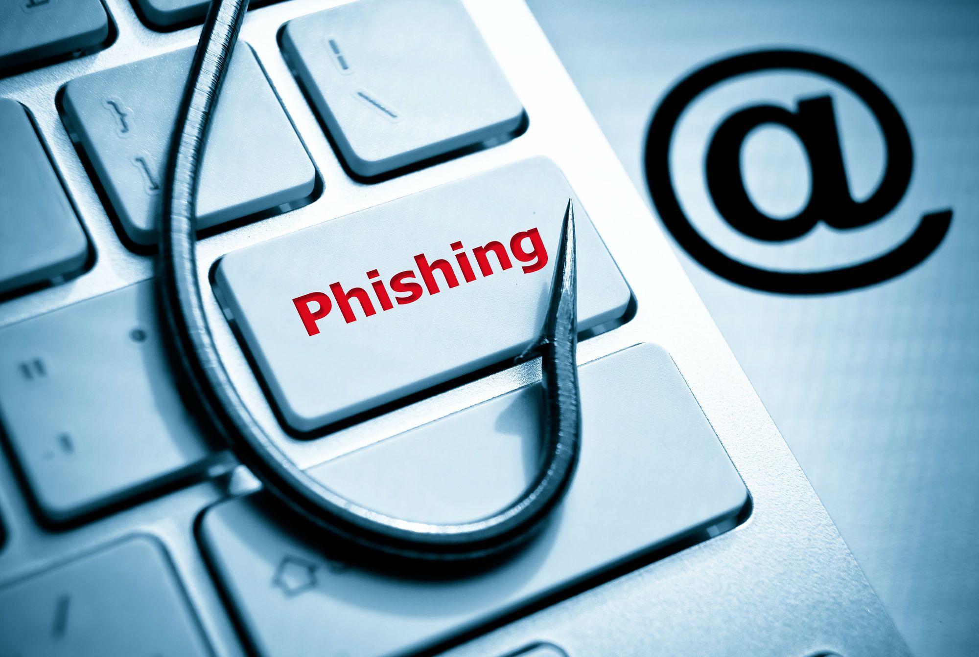 A fishing hook lies on top of a "phishing" key on computer keyboard, which sits next to an @ symbol - golden entertainment