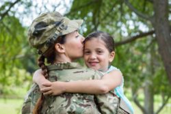 Military woman hugging daughter