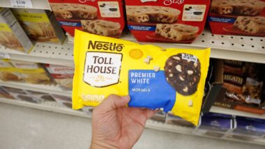A hand holds a package of Nestle Toll House premiere white morsels, on display at a local grocery store.