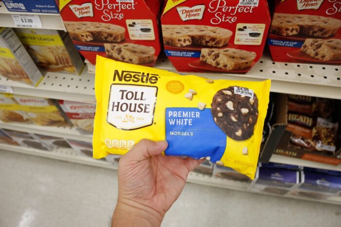 A hand holds a package of Nestle Toll House premiere white morsels, on display at a local grocery store.