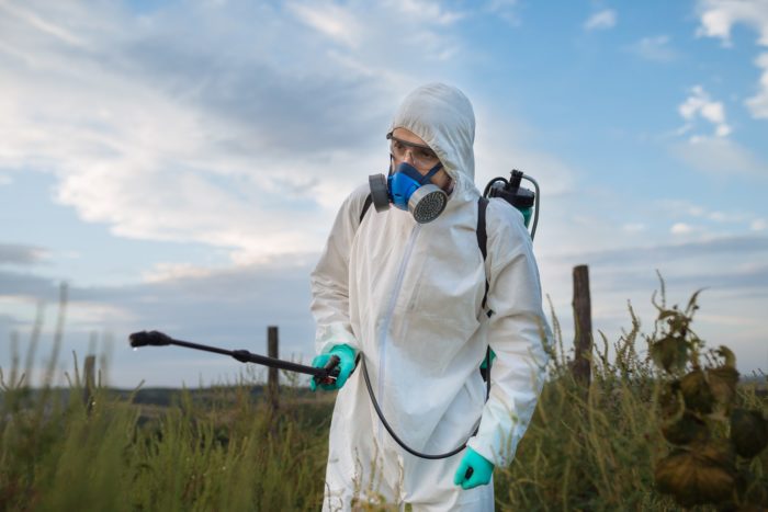 Worker spraying pesticide in protective gear