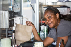 African American woman works the window of a food truck