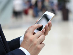 A man holds a cell phone as if ready to receive or send text.