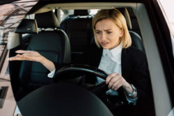 A frustrated woman behind the wheel of her vehicle appears exasperated with the car