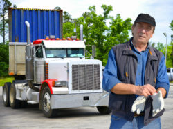 Mature man putting on gloves to start driving big rig truck.