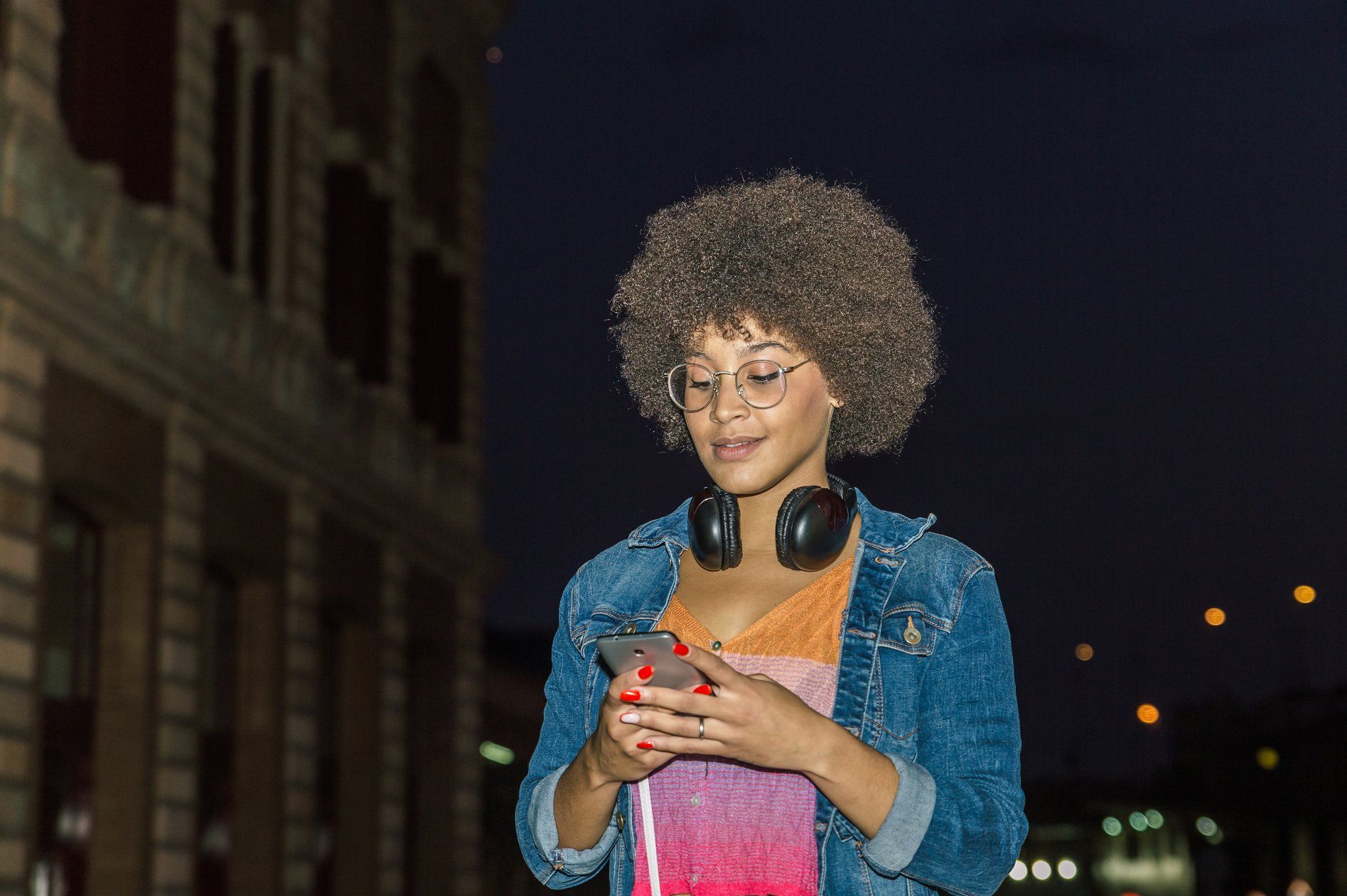 Young woman texts outside at night