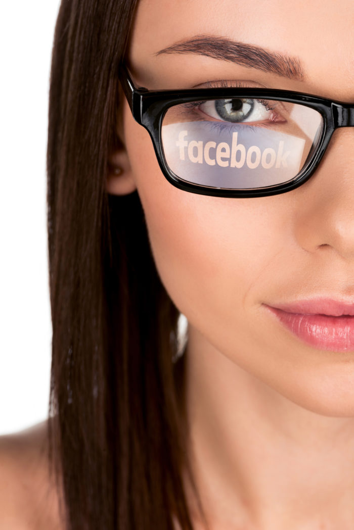 facebook logo reflected off of woman's eyeglasses