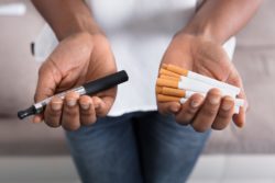 Woman's hands holding vape pen and cigarettes