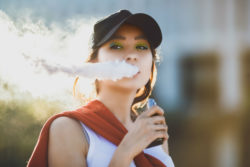 Young hipster woman vaping.