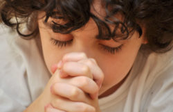 Close up of young boy praying with eyes closed