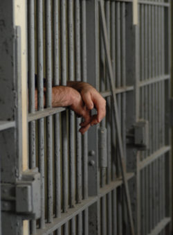 hands hanging out of prison cell regarding Bell Canada charging excessive fees for prison calls