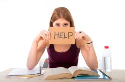 female student holding help sign