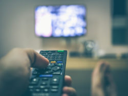person holding remote watching tv regarding Super Channel lawsuit over pirate devices