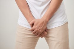 man with bladder pain, hands in front of body