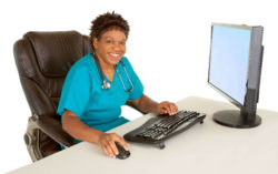Female doctor sits at desk and works on computer