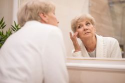 elderly woman looking in mirror while getting ready