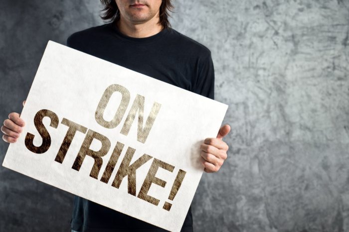 man holding a strike sign in his hands