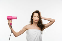 A woman looks at a hair dryer.