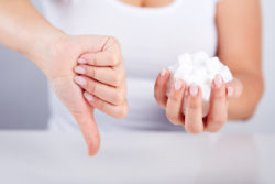 Woman holding sugar cubes with thumbs down