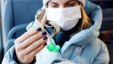 Woman wearing medical mask applying hand sanitizer regarding the Canadian consumer guide to the coronavirus