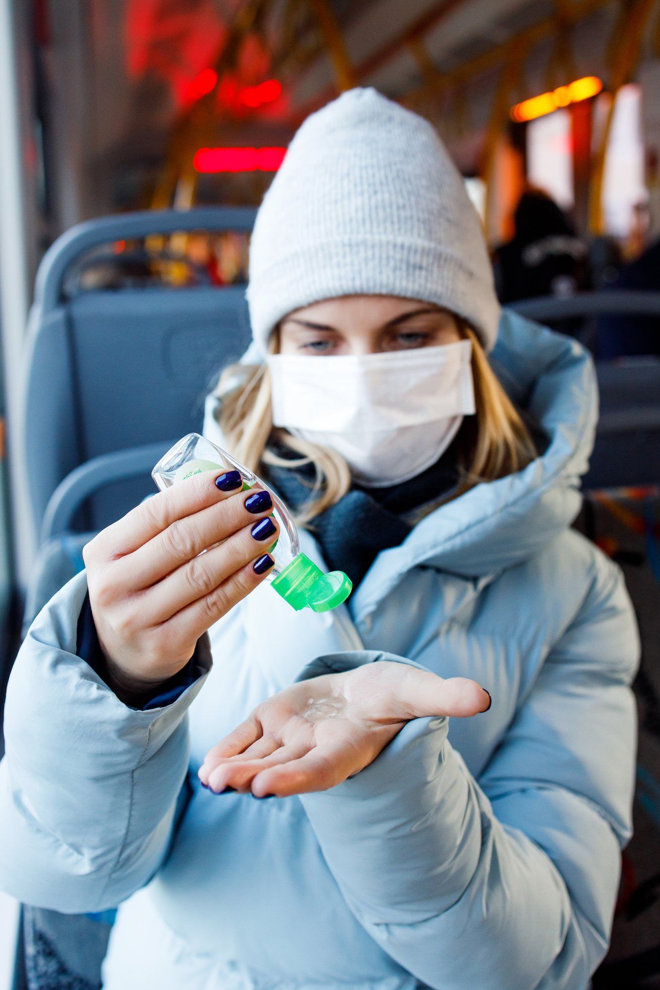 Woman wearing medical mask applying hand sanitizer regarding the Canadian consumer guide to the coronavirus