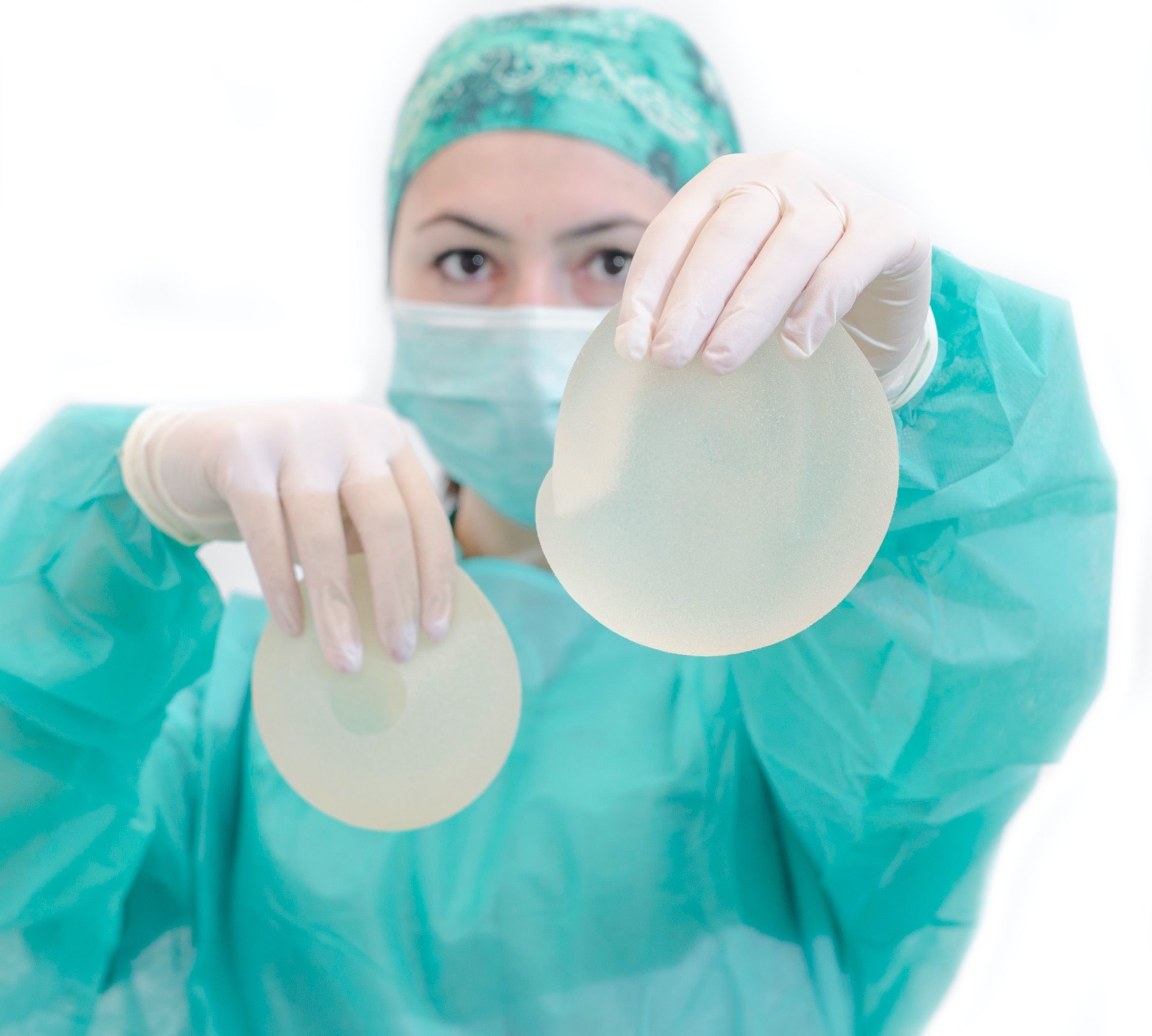 Doctor in scrubs holds out two different sizes of breast implants