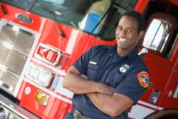 Male firefighter stands in front of truck