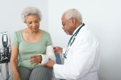 Doctor looks at cast on arm of elderly woman