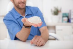 Male doctor holds breast implant