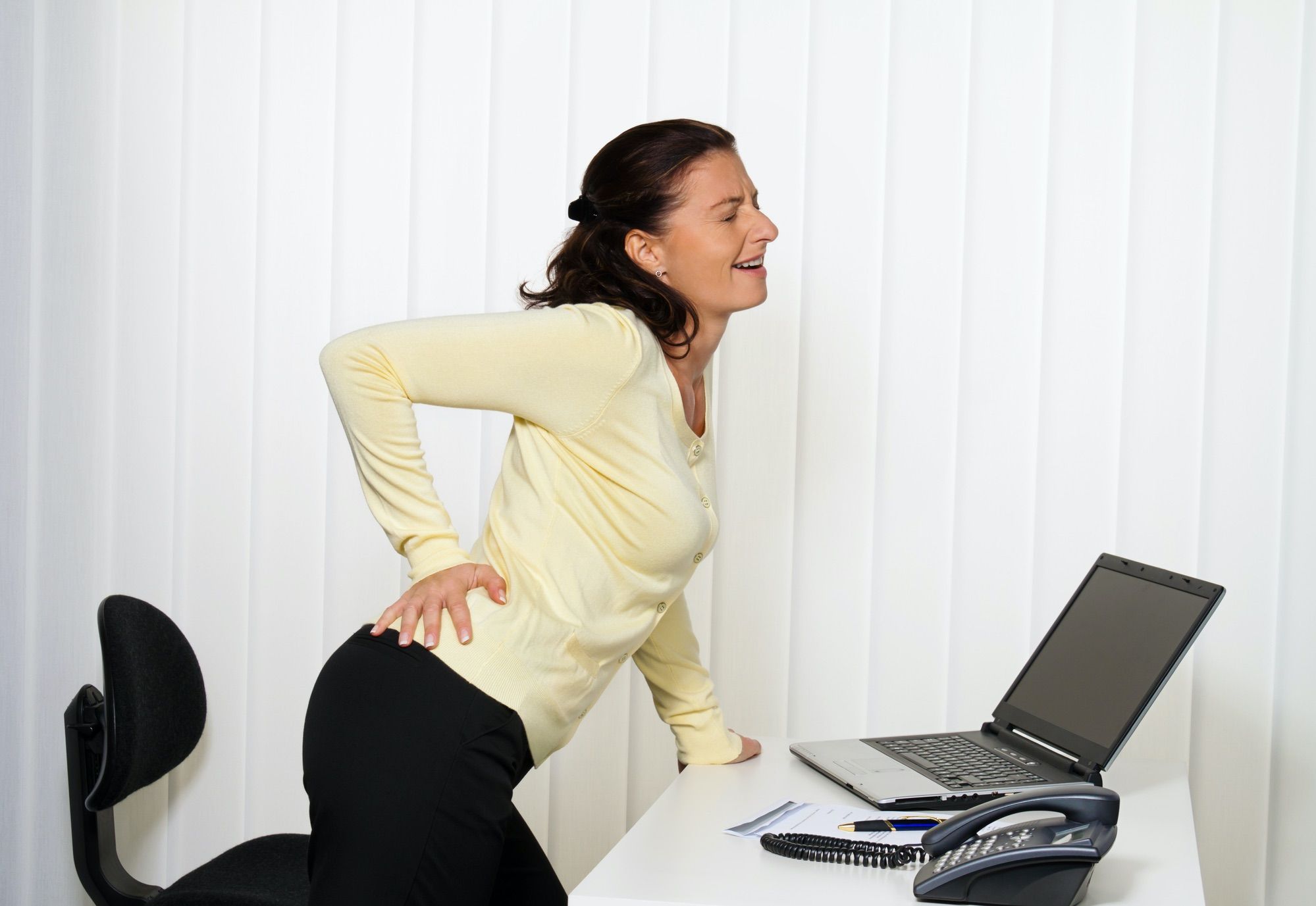 woman stands up from being seated at computer desk and has hip pain