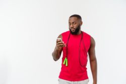 Athletic man with jump rope reads a text on his smartphone