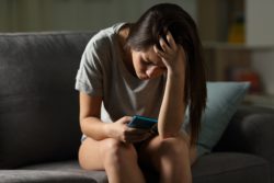 stressed teen on cell after Whisper information was leaked