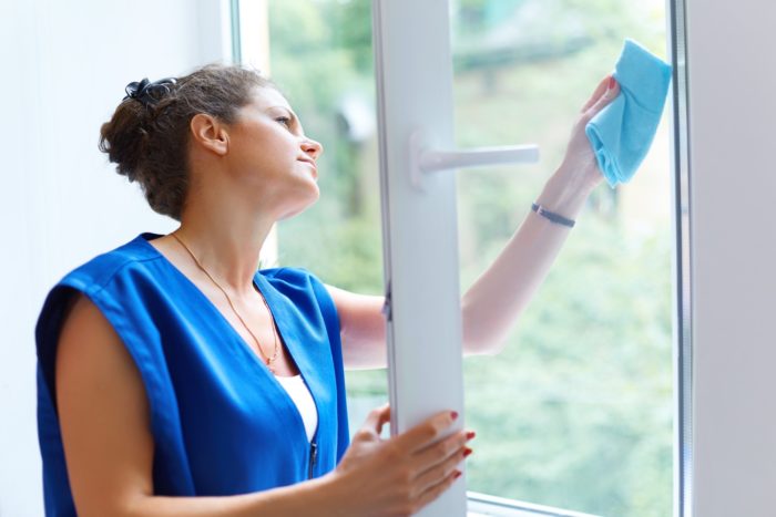 woman cleaning window with windex