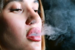 Closeup of young woman exhaling vapor