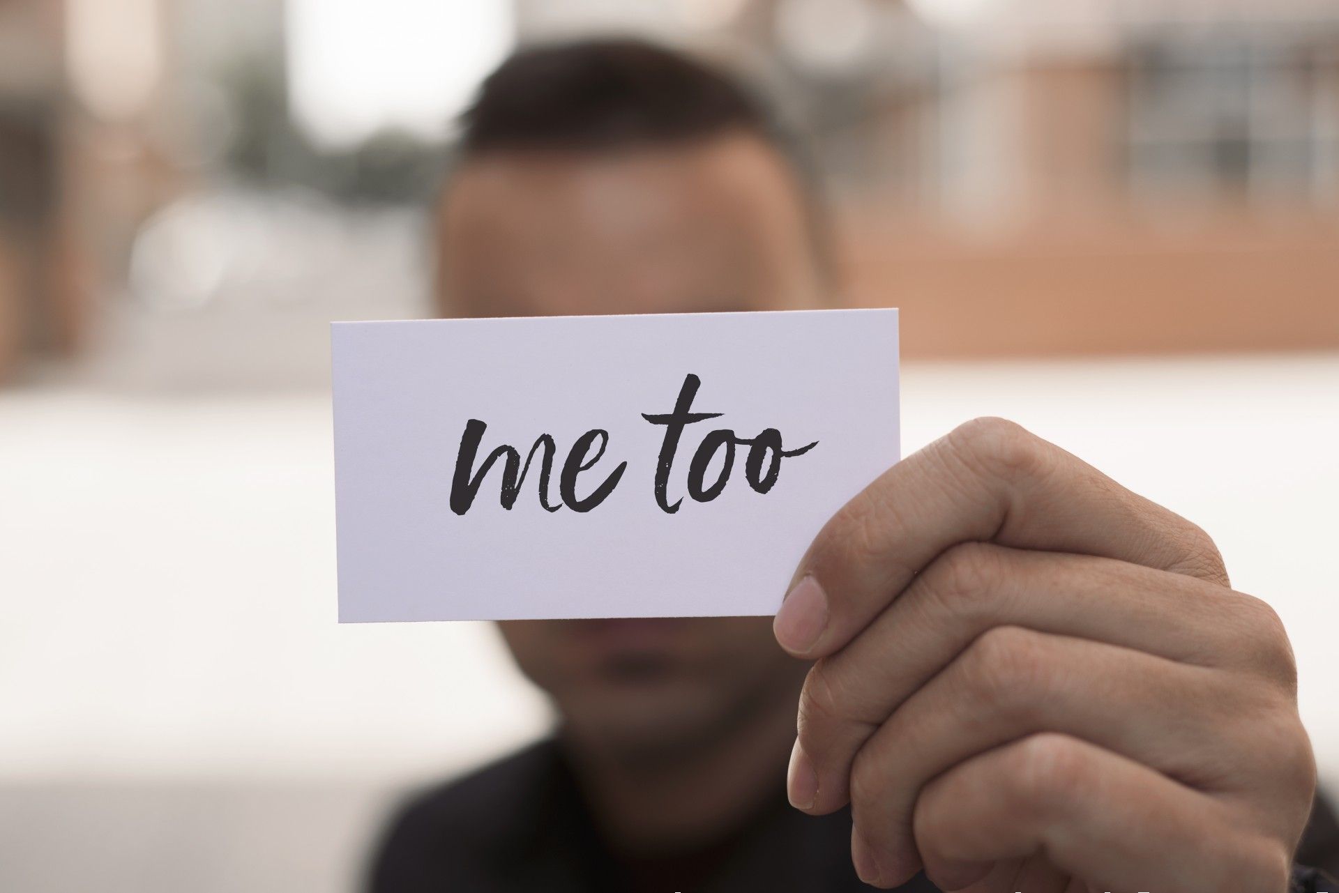 man holding #metoo sign in front of his face