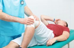 A man shows pain in a knee exam.
