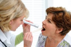 A doctor examines a woman with a sore throat.