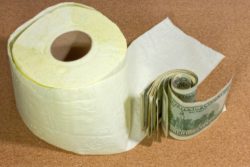 Toilet paper roll next to roll of hundred dollar bills represents price gouging