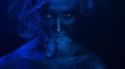 Woman vaping lit by dark blue light