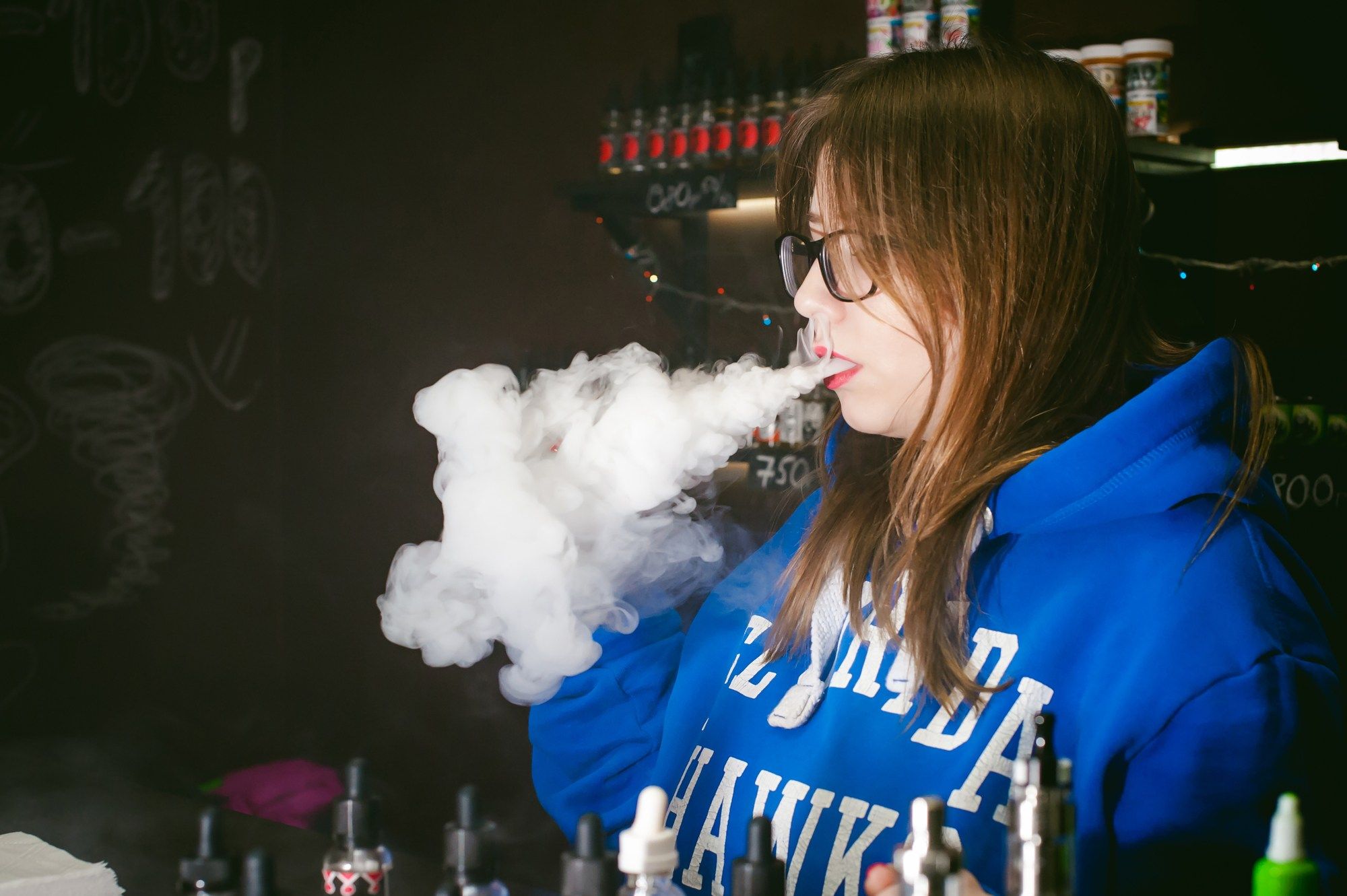 A woman vapes in an e-cigarette shop.
