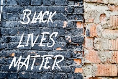 "Black Lives Matter" poster on black brick wall