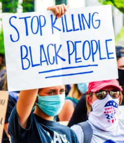Black Lives Matter protesters gathered together with signs saying "stop killing black people"