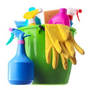 Colorful cleaning supplies in a green bucket sitting next to a blue spray bottle