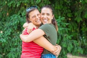 Two women smiling and hugging outdoors