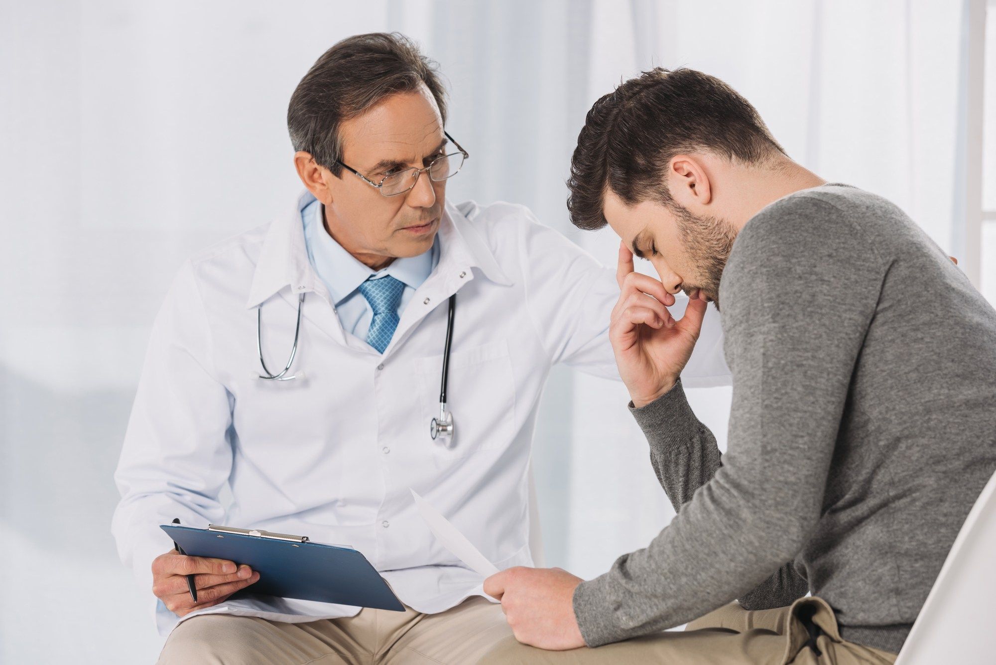 Male doctor comforts upset male patient