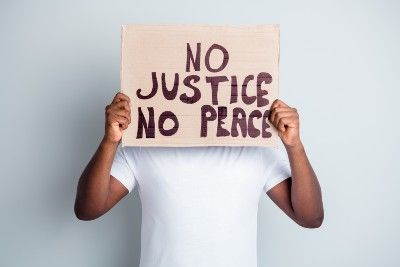 Man in white T-shirt holding sign that says "No Justice No Peace"